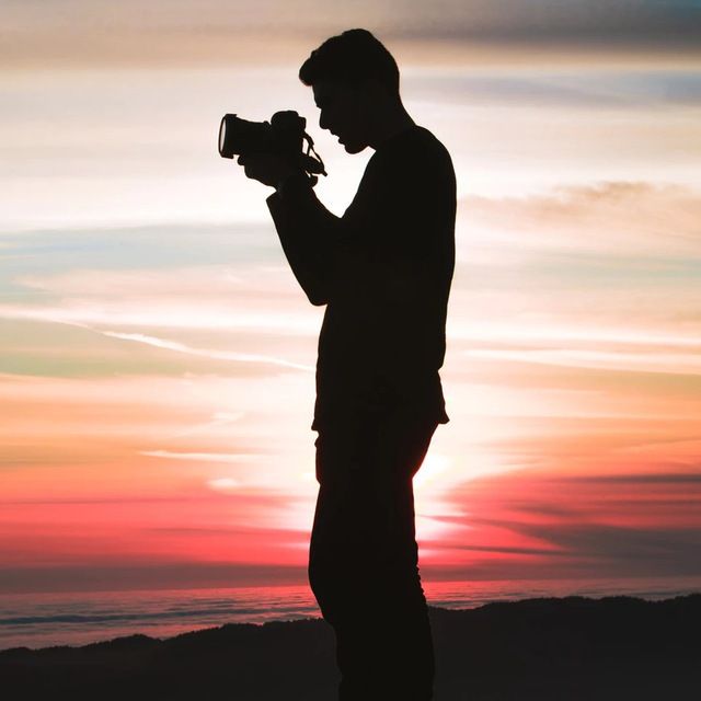 a man taking a photo of a sunset